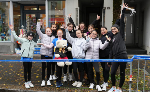 Gruppenfoto: Eisläuferinnen posieren mit den Händen in der Luft